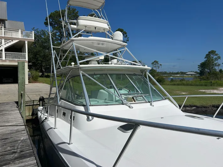 Ironman Yacht Photos Pics 2006 Rampage EXPRESS boat docked near a waterfront property under a clear blue sky.