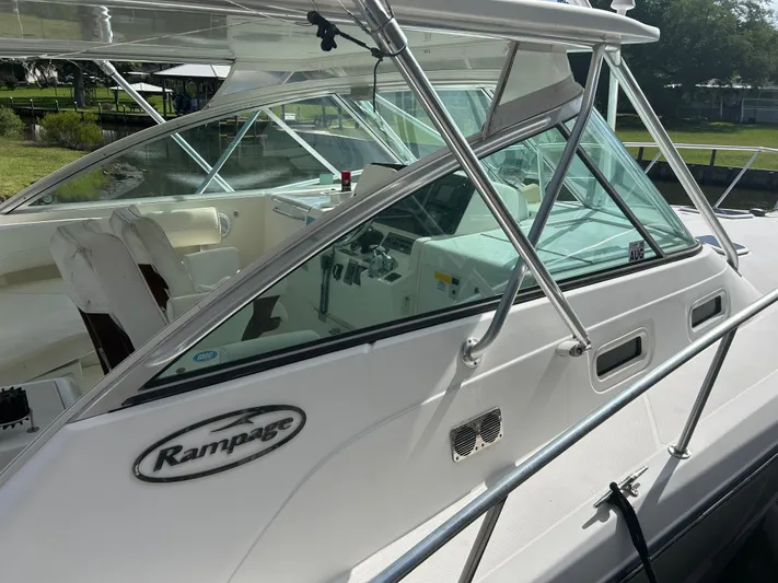 Ironman Yacht Photos Pics 2006 Rampage EXPRESS boat with sleek design and spacious cockpit, docked near greenery.