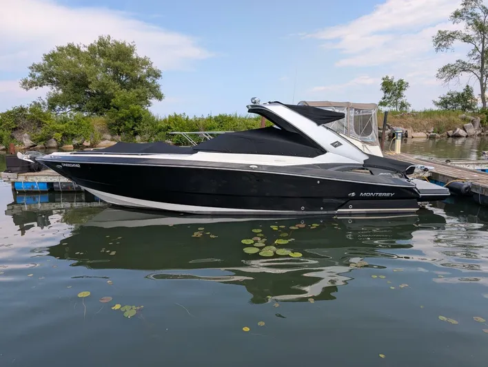  Yacht Photos Pics 2011 Monterey 328 SS boat docked on calm water, surrounded by greenery.