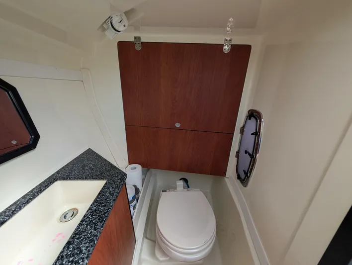  Yacht Photos Pics 2011 Monterey 328 SS boat bathroom with sink, toilet, and wooden cabinetry.