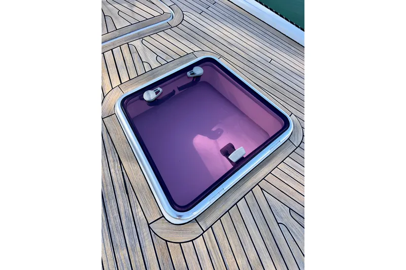 The Jonathan Shepard Yacht Photos Pics Teak deck hatch on 2006 Hanse 461e yacht, featuring purple-tinted glass.