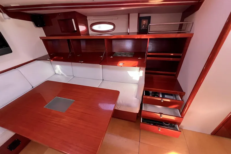 The Jonathan Shepard Yacht Photos Pics Interior of 2006 Hanse 461e yacht with wooden table, white seating, and storage cabinets.