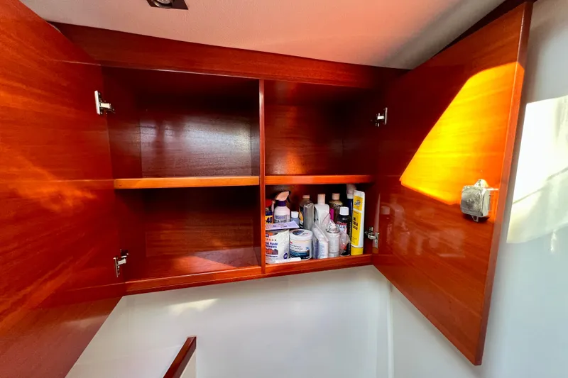 The Jonathan Shepard Yacht Photos Pics Wooden cabinet interior on 2006 Hanse 461e yacht, storing various bottles and supplies.