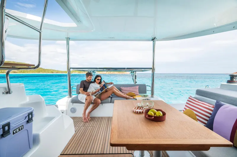  Yacht Photos Pics Couple relaxing on Lagoon 38 catamaran, 2026 model, with ocean view and cozy seating.