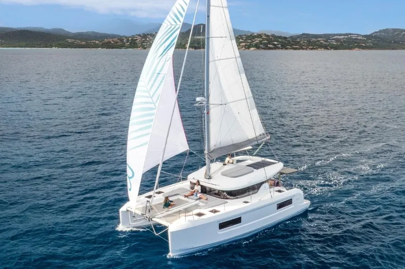  Yacht Photos Pics 2026 Lagoon 38 catamaran sailing on open sea with passengers relaxing on deck.