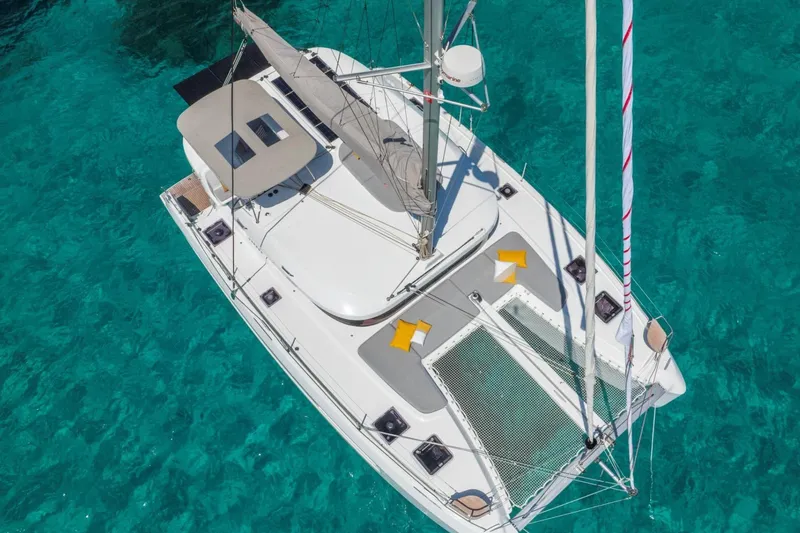  Yacht Photos Pics Aerial view of 2026 Lagoon 38 catamaran sailing on clear turquoise water.