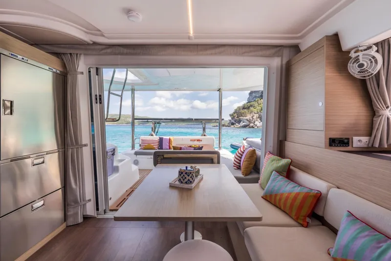  Yacht Photos Pics Luxurious interior of 2026 Lagoon 38 yacht with ocean view and colorful cushions.