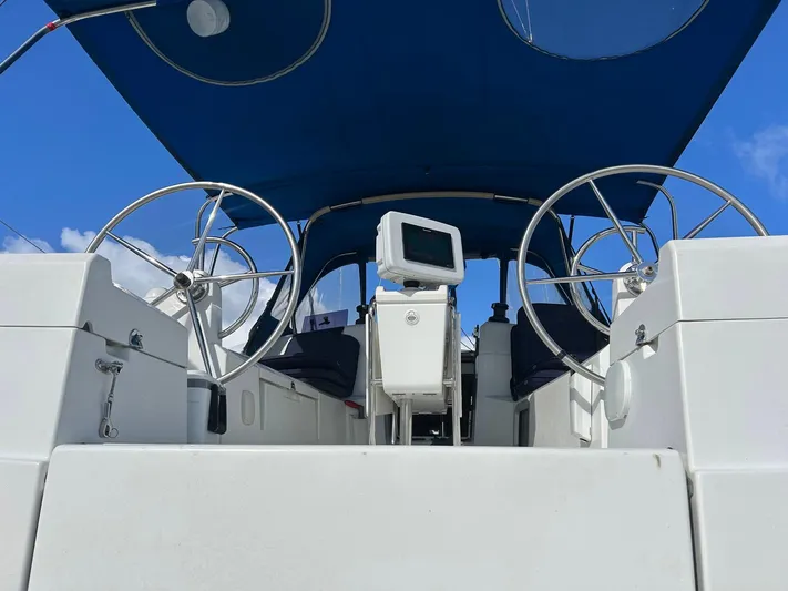 Layover Yacht Photos Pics 2018 Jeanneau Sun Odyssey 389 sailboat cockpit with dual steering wheels and blue canopy.