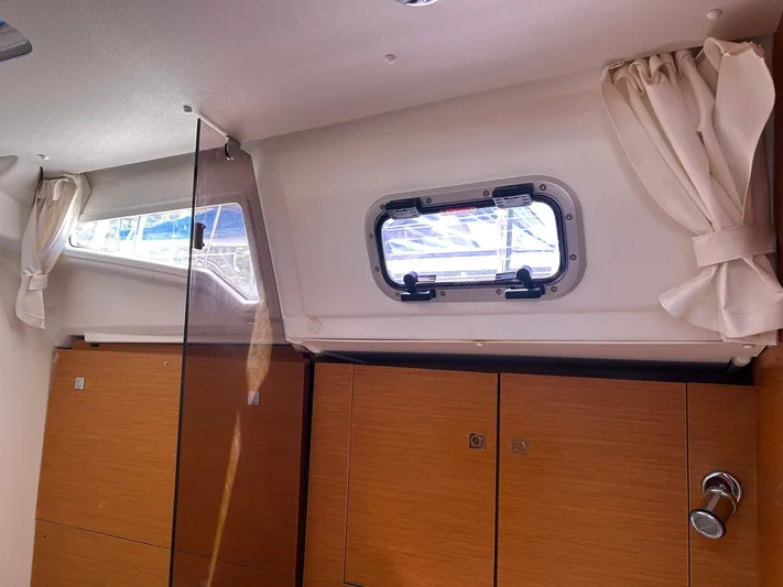 Layover Yacht Photos Pics Interior of 2018 Jeanneau Sun Odyssey 389 yacht with wooden cabinets and porthole window.
