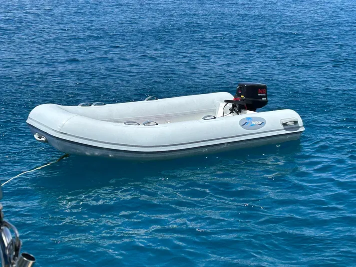 Layover Yacht Photos Pics Inflatable dinghy floating on clear blue water, near Jeanneau Sun Odyssey 389, 2018 model.