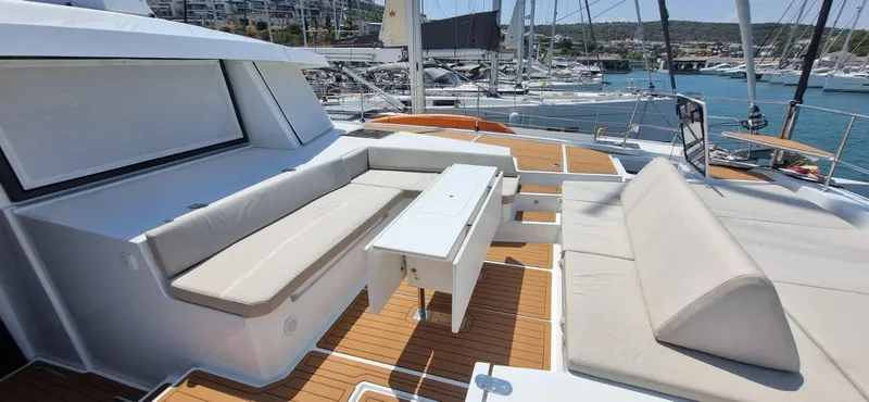  Yacht Photos Pics Luxurious 2024 Bali 5.4 yacht deck with comfortable seating and table, docked at marina.