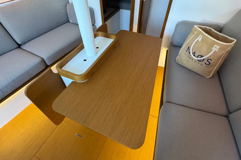 Yacht Photos Pics Interior of 2023 Beneteau First 36 yacht with wooden table and gray seating.
