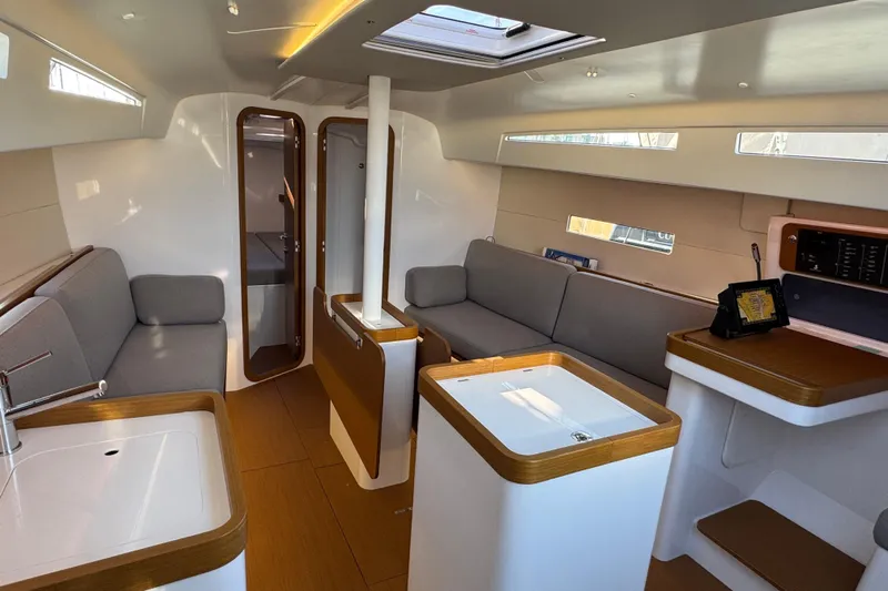  Yacht Photos Pics 2023 Beneteau First 36 interior with modern design, featuring seating, kitchenette, and natural lighting.