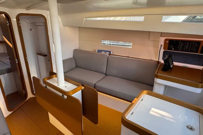  Yacht Photos Pics 2023 Beneteau First 36 interior with modern design, featuring a cozy gray sofa and wooden accents.