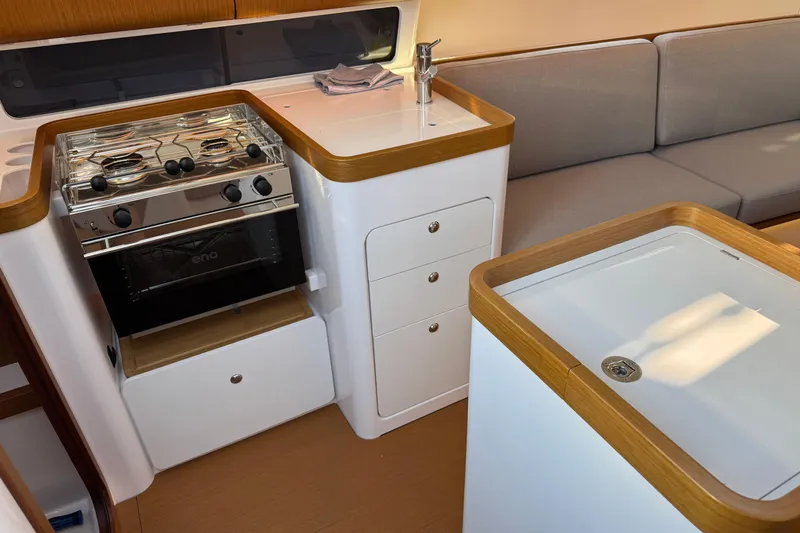  Yacht Photos Pics Modern kitchen interior of 2023 Beneteau First 36 yacht with stove and seating area.