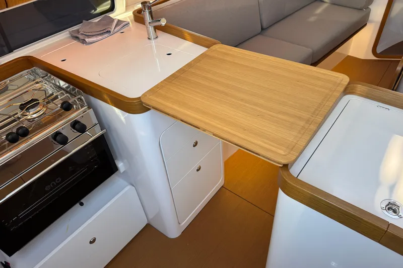  Yacht Photos Pics 2023 Beneteau First 36 yacht interior kitchen with stove, sink, and wooden countertop.