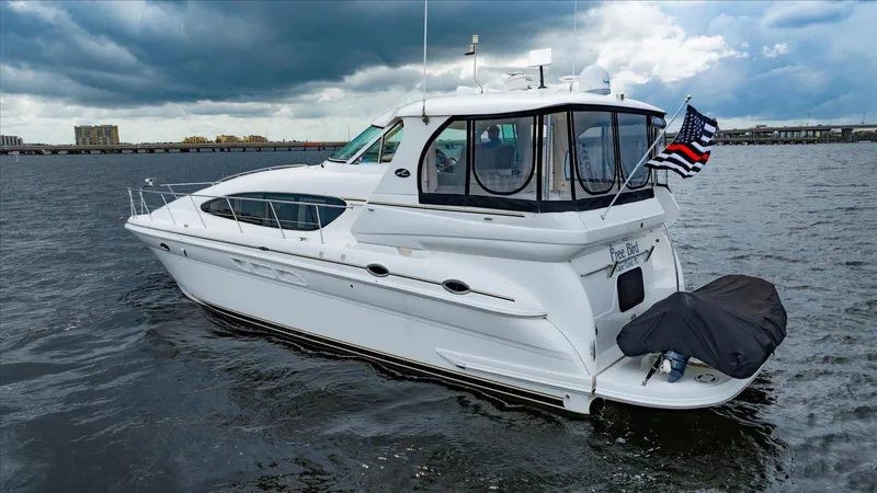 Free Bird Yacht Photos Pics 2003 Sea Ray 480 Motor Yacht on water, cloudy sky, American flag displayed.