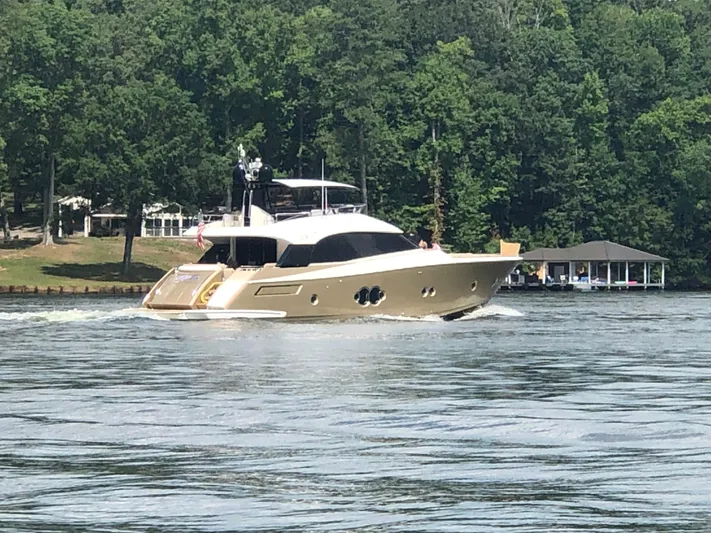 Rebellion Yacht Photos Pics 2012 Monte Carlo Yachts 76 cruising on a serene lake with lush green trees.