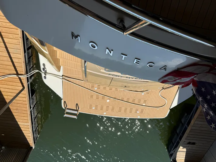 Rebellion Yacht Photos Pics Monte Carlo Yachts 76, 2012 model, docked with American flag and water reflections.