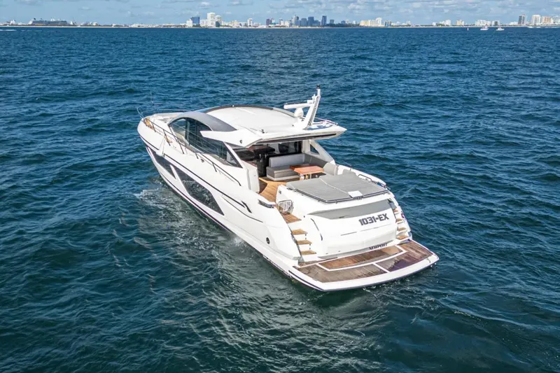  Yacht Photos Pics 2020 Sunseeker Predator 74 yacht cruising on open water with city skyline in background.