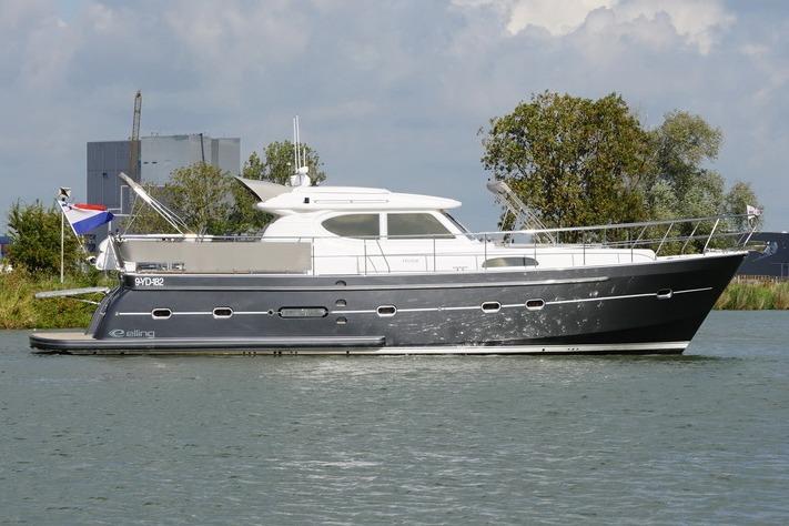 2014 Elling E4 yacht cruising on a calm river with trees in the background.