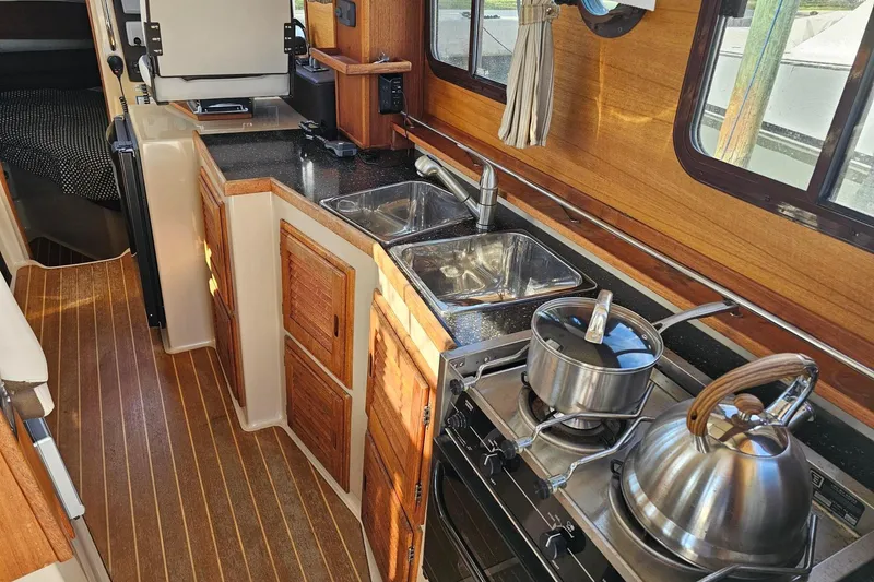  Yacht Photos Pics 2014 Ranger Tugs R 31 boat kitchen with stove, sink, and wooden cabinetry.