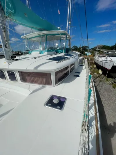 Unfettered Yacht Photos Pics 2015 Lagoon 450 F catamaran with turquoise canopy, docked under clear blue sky.
