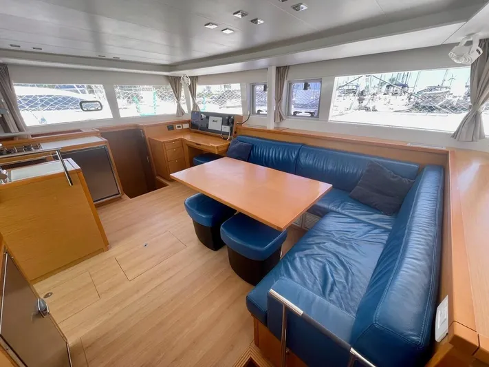 Unfettered Yacht Photos Pics Interior of 2015 Lagoon 450 F yacht with blue seating and wooden table.
