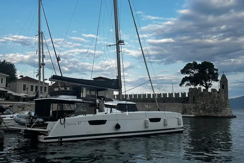 Talila Yacht Photos Pics 2022 Fountaine Pajot Tanna 47 catamaran docked near historic stone fortress.