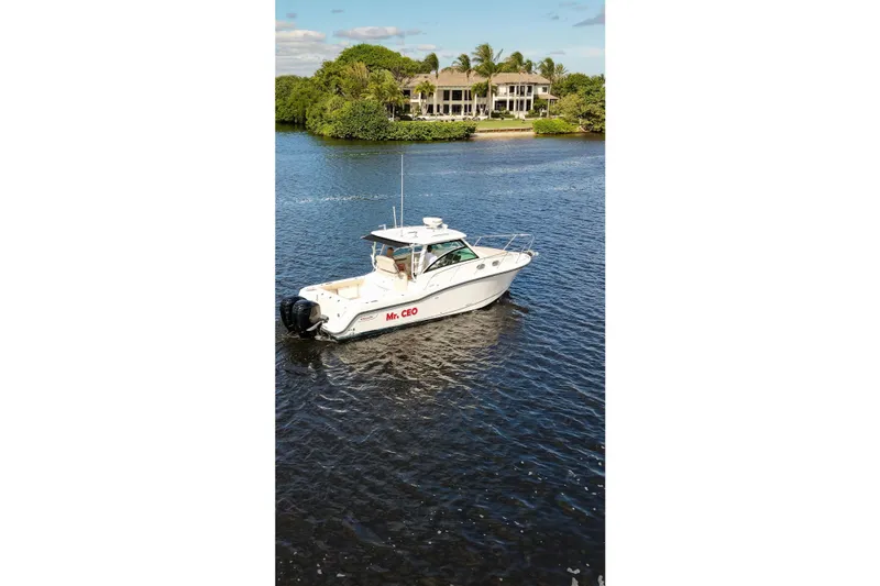 Mr Ceo Yacht Photos Pics 2015 Boston Whaler 315 Conquest boat on a serene waterway near a luxury home.