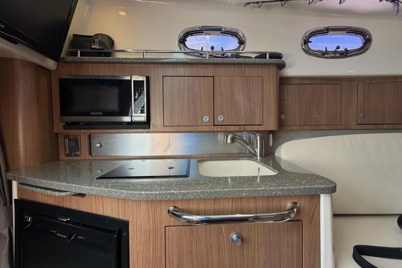 Mr Ceo Yacht Photos Pics 2015 Boston Whaler 315 Conquest interior kitchen with microwave, sink, and wooden cabinetry.