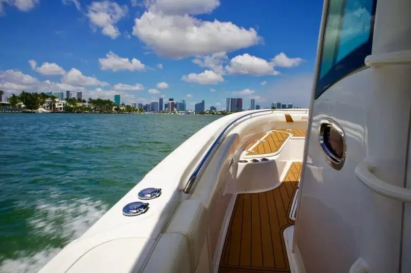  Yacht Photos Pics 2013 Boston Whaler 320 Outrage cruising near city skyline under blue sky.