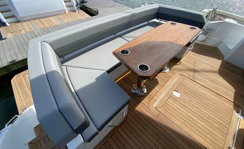 Radiant Yacht Photos Pics Luxurious seating area on 2022 Cruisers Yachts 60 Fly with wooden table and cup holders.