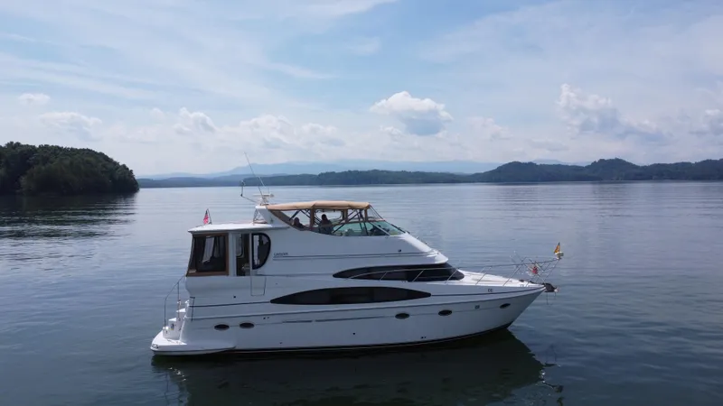  Yacht Photos Pics 2002 Carver 466 Motor Yacht cruising on a serene lake under a clear sky.