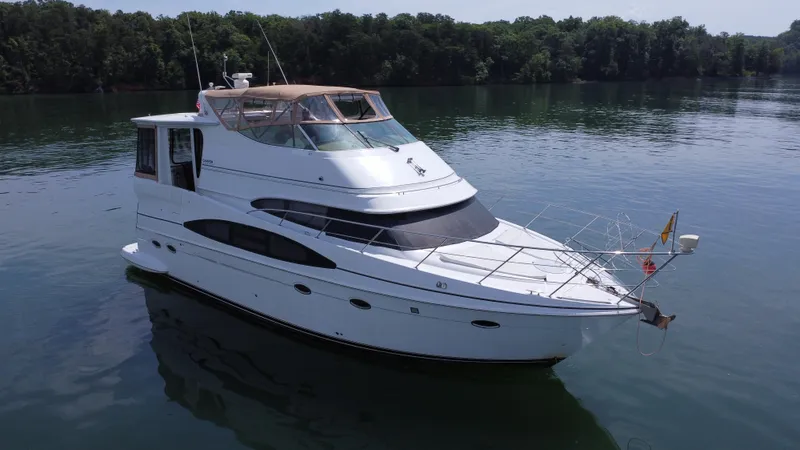  Yacht Photos Pics 2002 Carver 466 Motor Yacht on calm water, surrounded by lush greenery.
