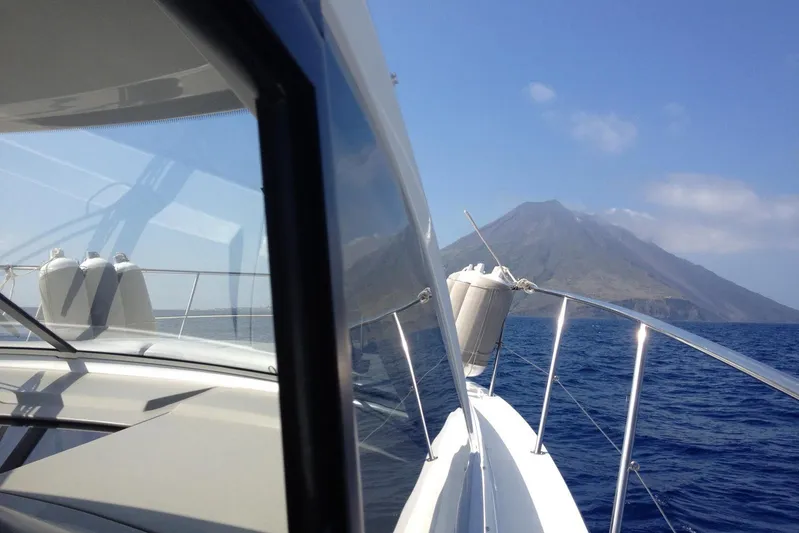  Yacht Photos Pics Beneteau Gran Turismo 44 yacht cruising near a volcanic island, clear blue sky.