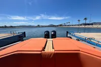 2023 SACS Strider 15 FB yacht with orange seating, docked by a scenic waterfront.