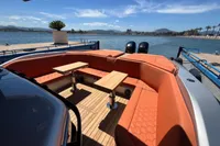 2023 SACS Strider 15 FB luxury yacht with orange seating and wooden deck, docked by the water.