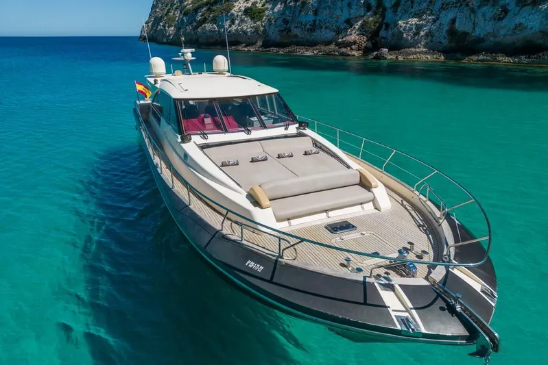 Vintage Yacht Photos Pics Luxurious 2006 Guy Couach 2100 yacht anchored in clear turquoise waters near rocky cliffs.