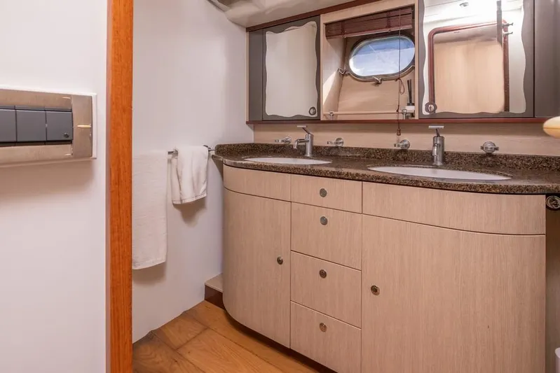 Vintage Yacht Photos Pics Luxury yacht bathroom with dual sinks, wooden cabinetry, and porthole window on Guy Couach 2100, 2006 model.