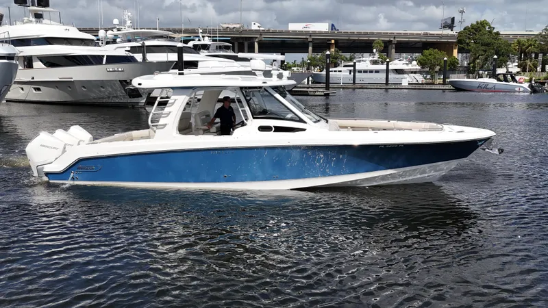 Yacht Kings Yacht Photos Pics 2020 Boston Whaler 350 Realm boat cruising in a marina, featuring a sleek blue and white design.