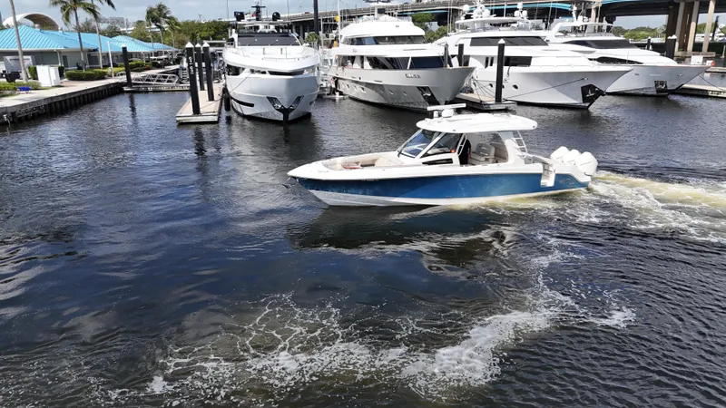 Yacht Kings Yacht Photos Pics 2020 Boston Whaler 350 Realm cruising in marina with luxury yachts in background.