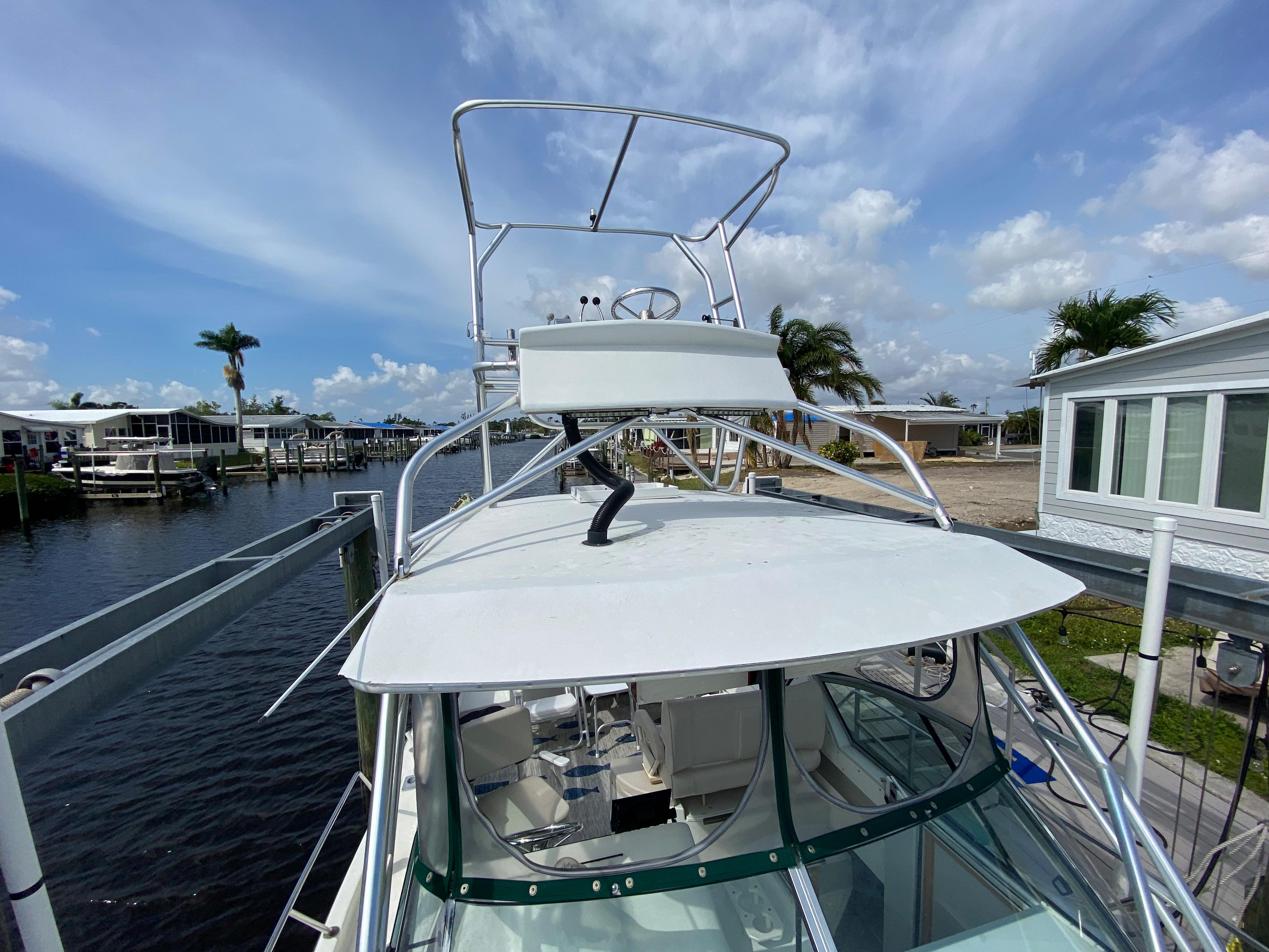 1997 Stamas 310 Express boat docked at a marina with clear skies.