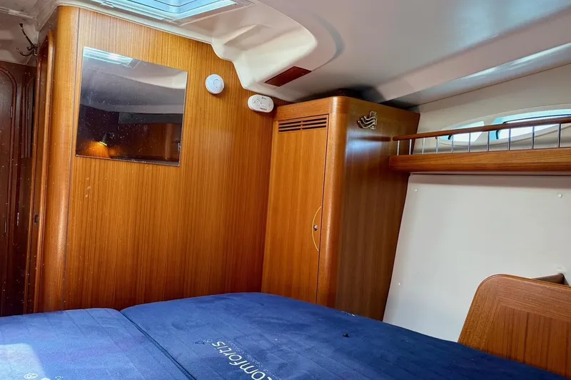  Yacht Photos Pics Interior cabin of 2006 X-Yachts X-50, featuring wooden paneling and blue bedding.