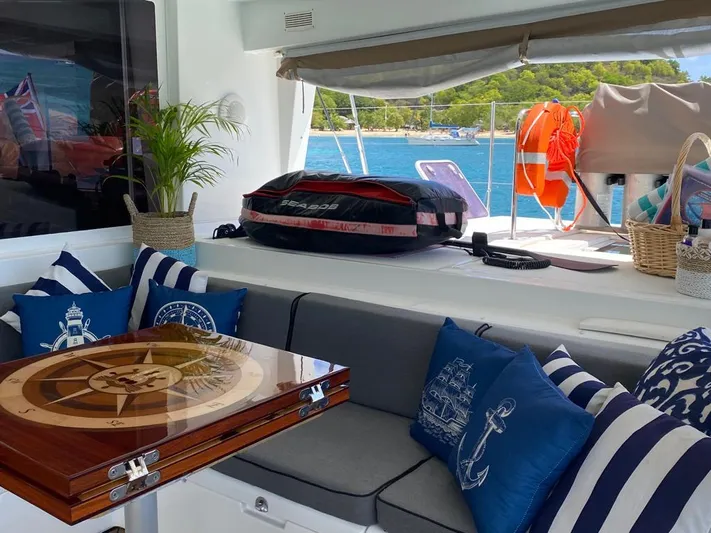 The Recipe Yacht Photos Pics Luxurious Lagoon 560 yacht interior with nautical decor, featuring striped cushions and a wooden table.