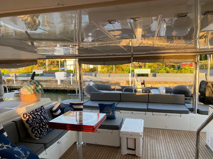 The Recipe Yacht Photos Pics Luxurious Lagoon 560 catamaran interior with elegant seating and table, docked at a marina.