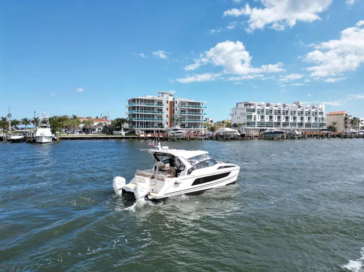 Yaffa Yacht Photos Pics 2021 Aquila 36 boat cruising on a sunny day near waterfront buildings.