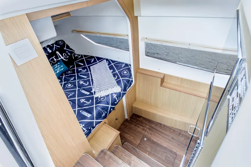 Yaffa Yacht Photos Pics Cozy cabin interior of 2021 Aquila 36 with nautical-themed bedding and wooden accents.