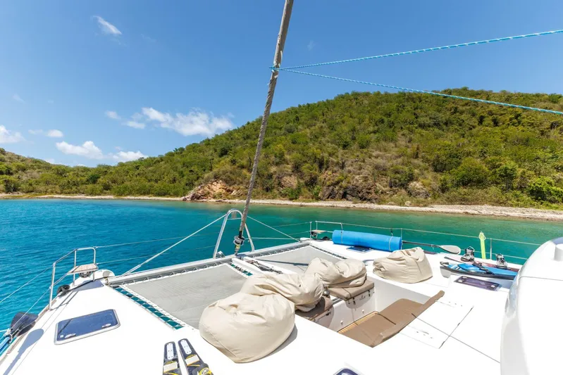 Azuria Yacht Photos Pics Lagoon 500 catamaran deck with bean bags, anchored near lush green island, clear blue water.