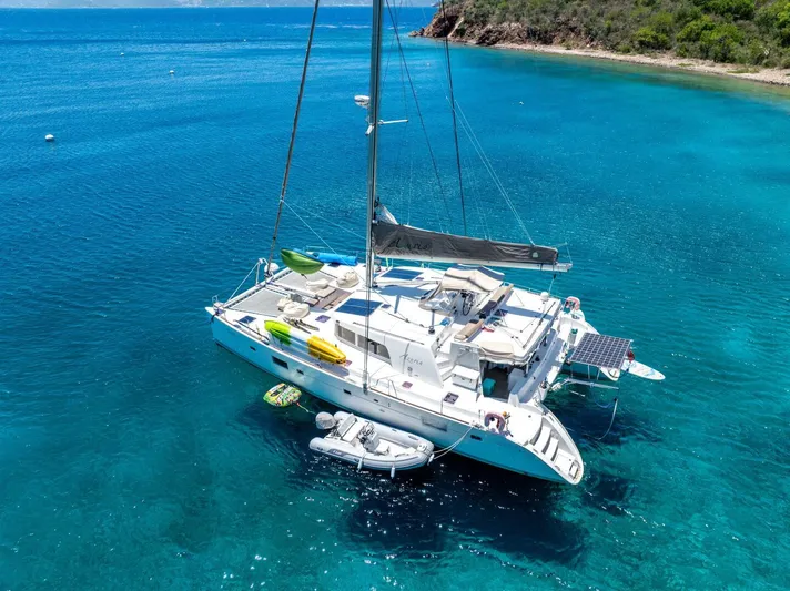 Azuria Yacht Photos Pics 2011 Lagoon 500 catamaran anchored in clear blue waters near a lush coastline.